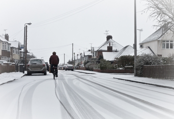 Hiring A Skip In Winter- man cycling down a street in snow