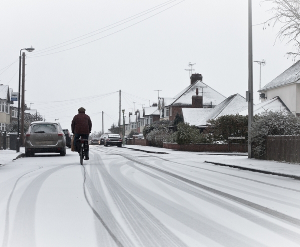 Hiring A Skip In Winter- man cycling down a street in snow