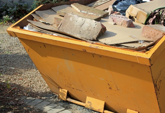 Yellow skip filled with bricks and cupboards