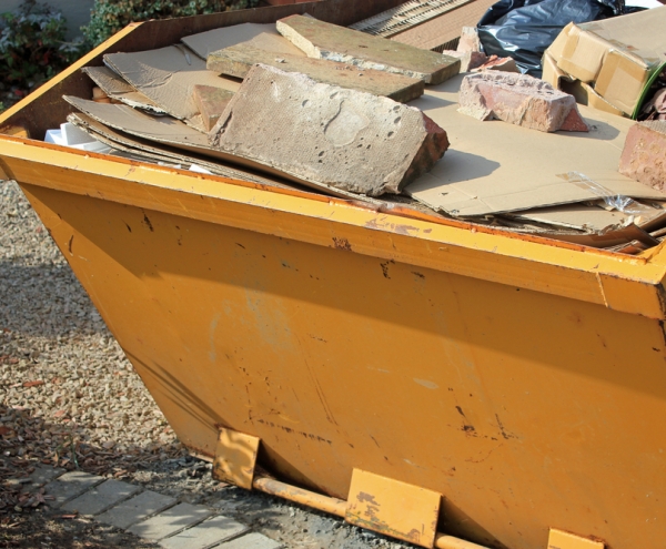 Yellow skip filled with bricks and cupboards