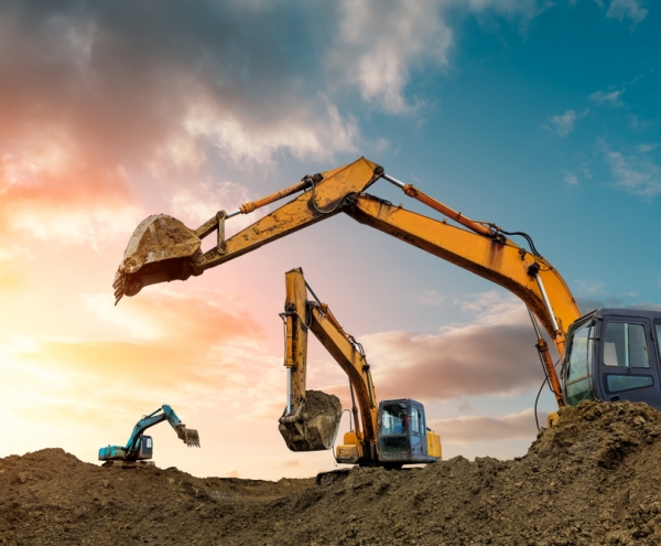 Three diggers digging up soil with sun shining in the background