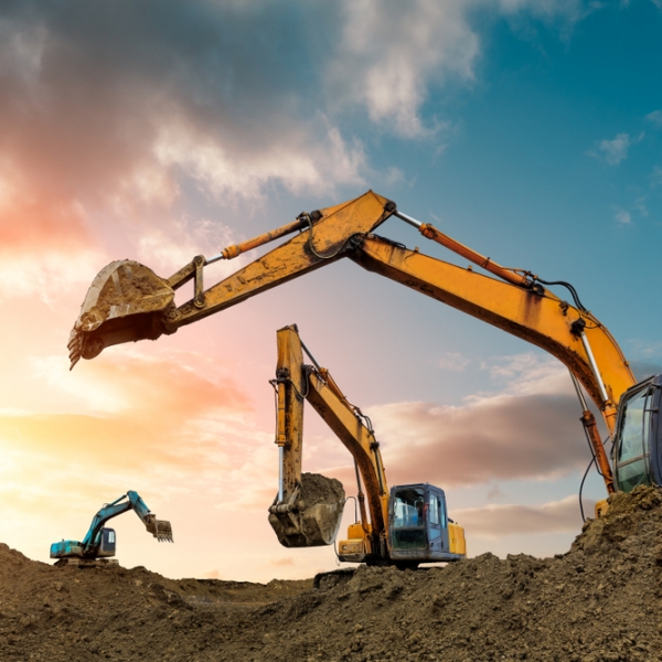 Three diggers digging up soil with sun shining in the background